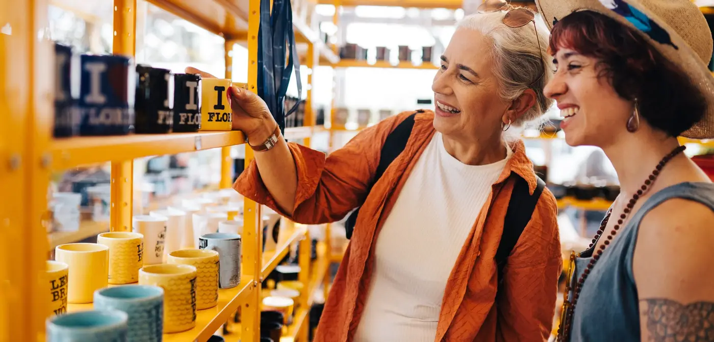 Two women shopping, smiling and looking at mugs